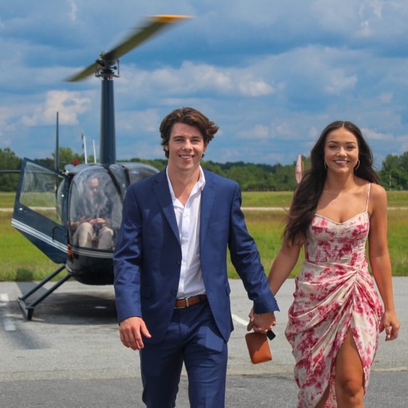 a couple in front of a helicopter