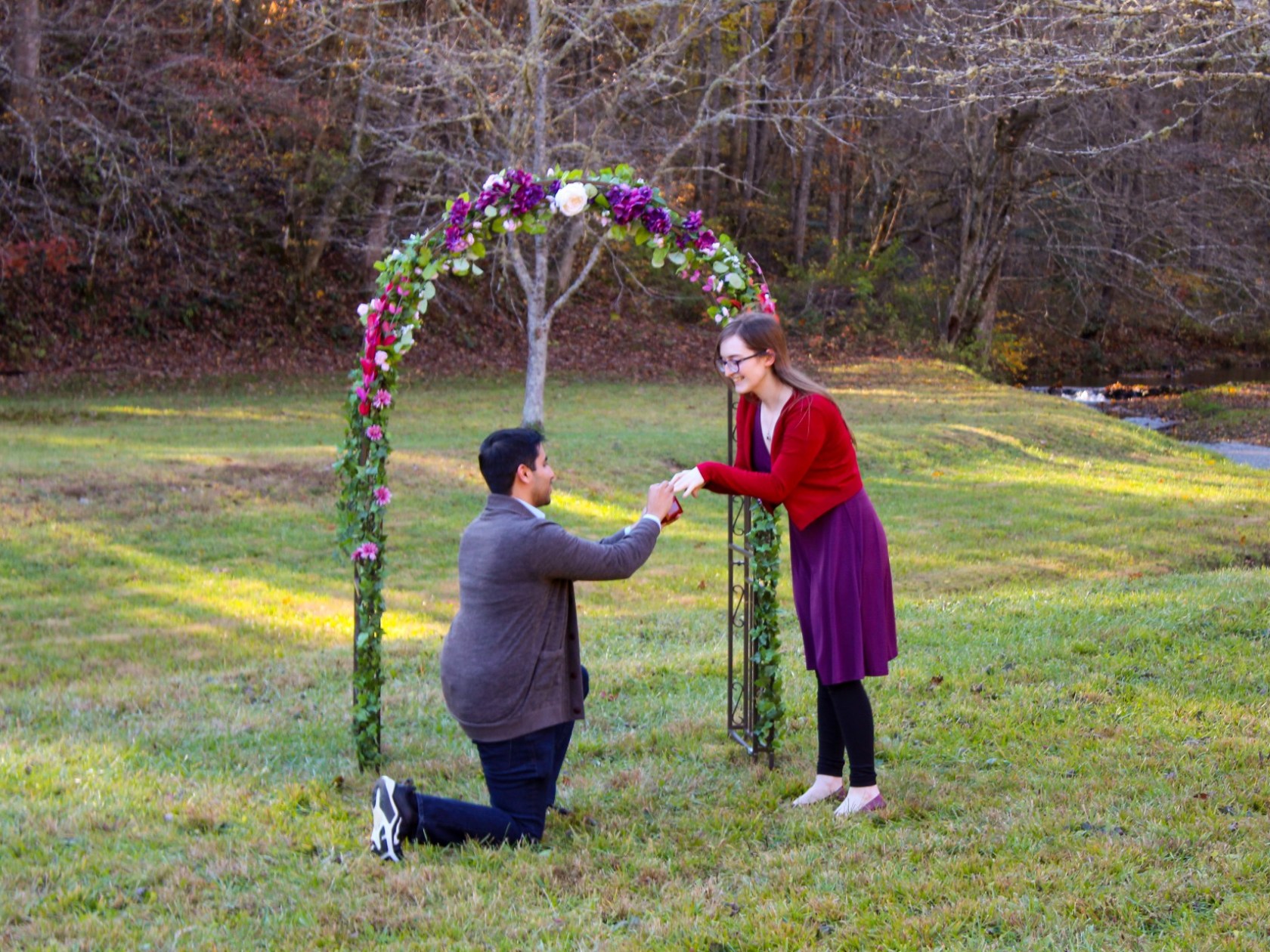 a man proposing to a woman in a grassy field