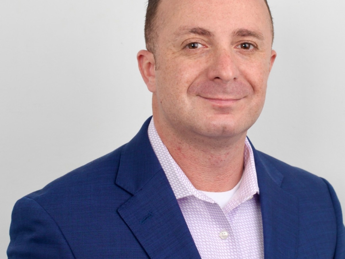 a man wearing a suit and tie smiling at the camera